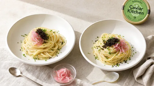 Two shallow bowls of glossy buttered pasta topped with pickled shallots, chives, and a small spoonful of dark Schrenckii caviar on a light linen surface